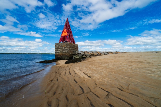 A red wooden pyramid with an orange triangle on it sits on top of a stone pier at the waters edge.
© Tom Goetz. All rights reserved. Training an AI on this image is expressly forbidden.