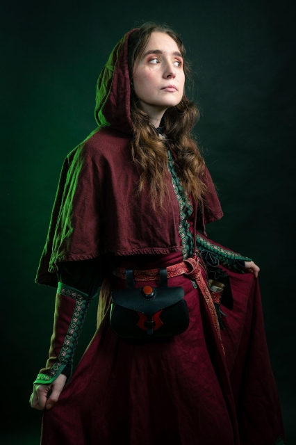 Photo of what could be a medieval vampire with a red and green dress, red hood and embossed vegtan leather belt and belt accessories. Has some scars but looks quite nice for a young undead creature ! ^^