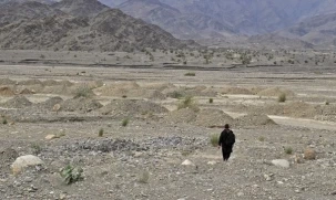 An Afghan man walks across rocky terrain